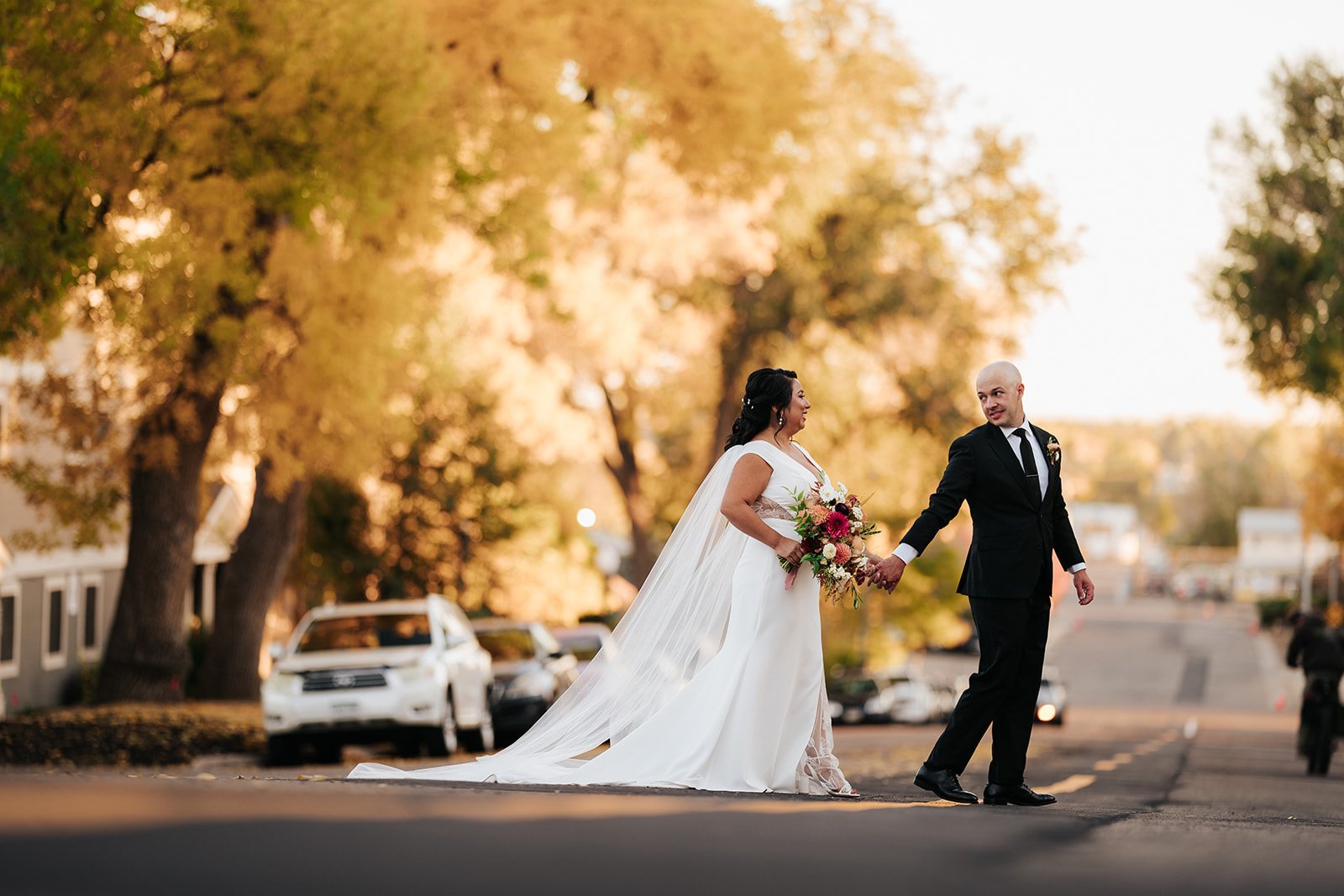 Bride and groom crossing the road at outdoor fall wedding in Colorado